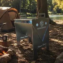 B.C VULKAN de pé num acampamento sob as árvores, com o logo BC Churrasqueiras na lateral